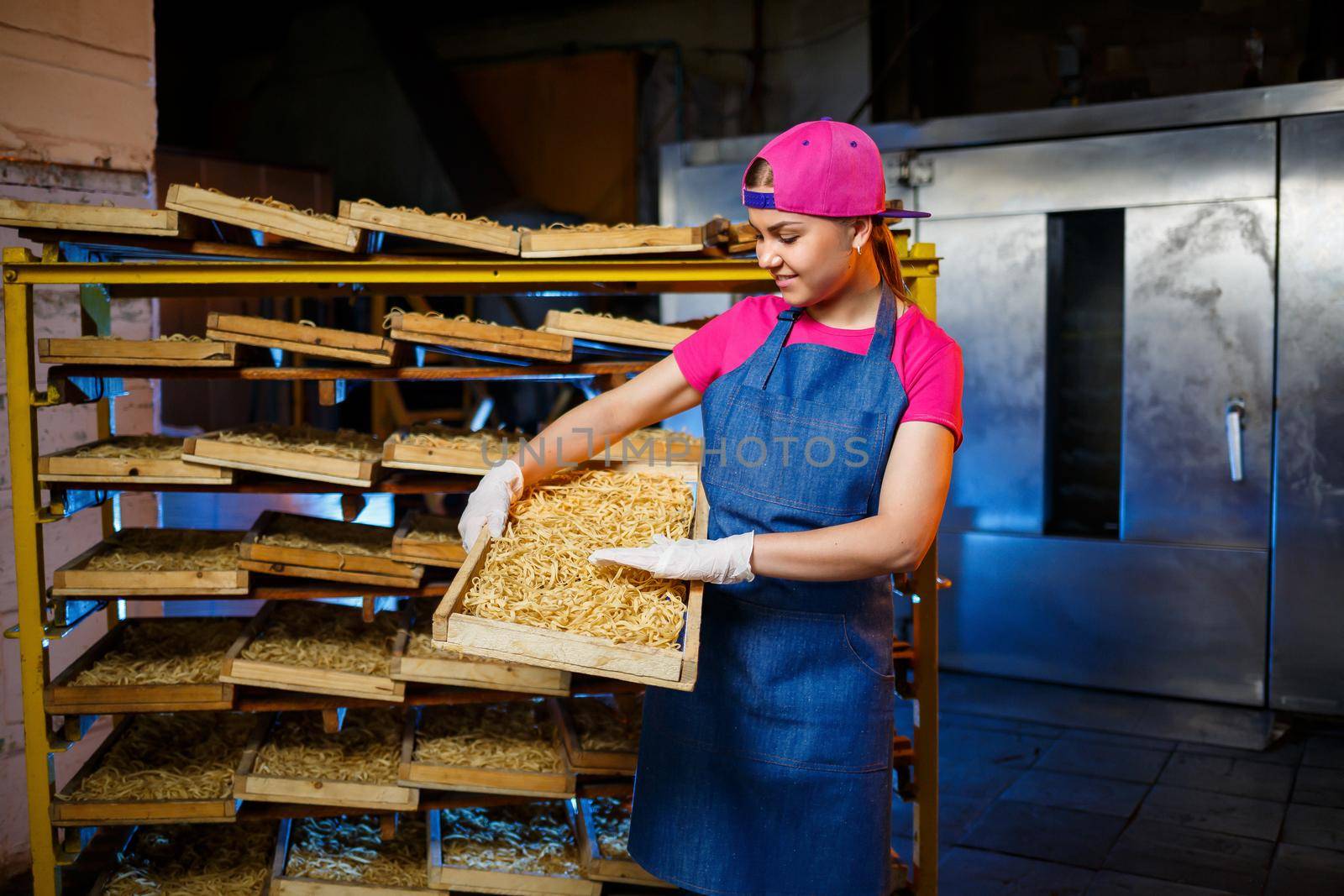 Make the noodles. Pasta factory. Spaghetti production. Raw pasta. Worker with a box of pasta. Girl works in the production of pasta by Dmitrytph