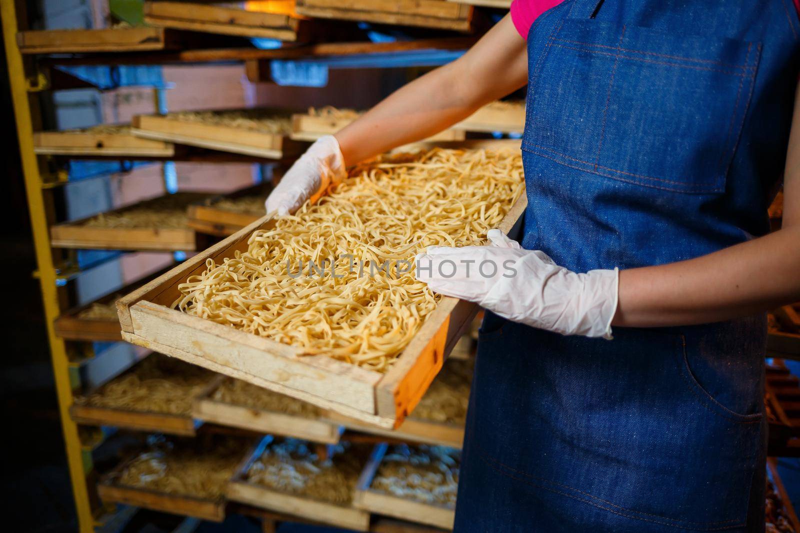 The girl works on the production of spaghetti. Making noodles. Pasta factory. Stage production of pasta. Raw noodles. Worker with a box of pasta.