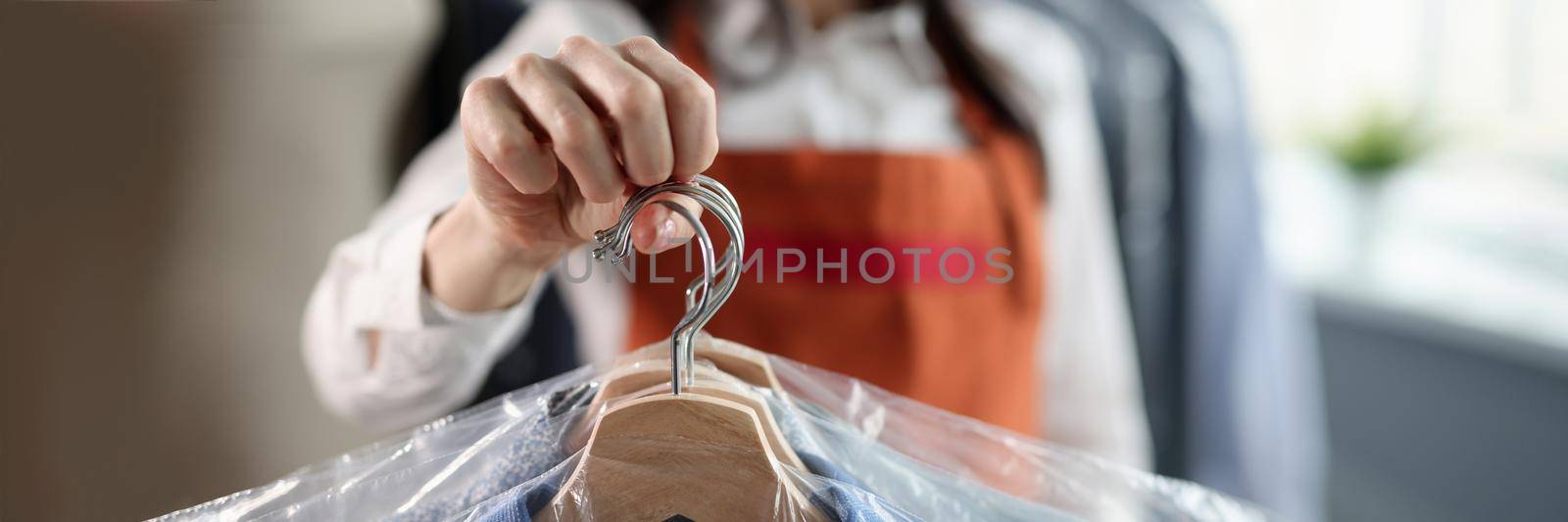 Professional worker keeps clean clothes on hangers by kuprevich