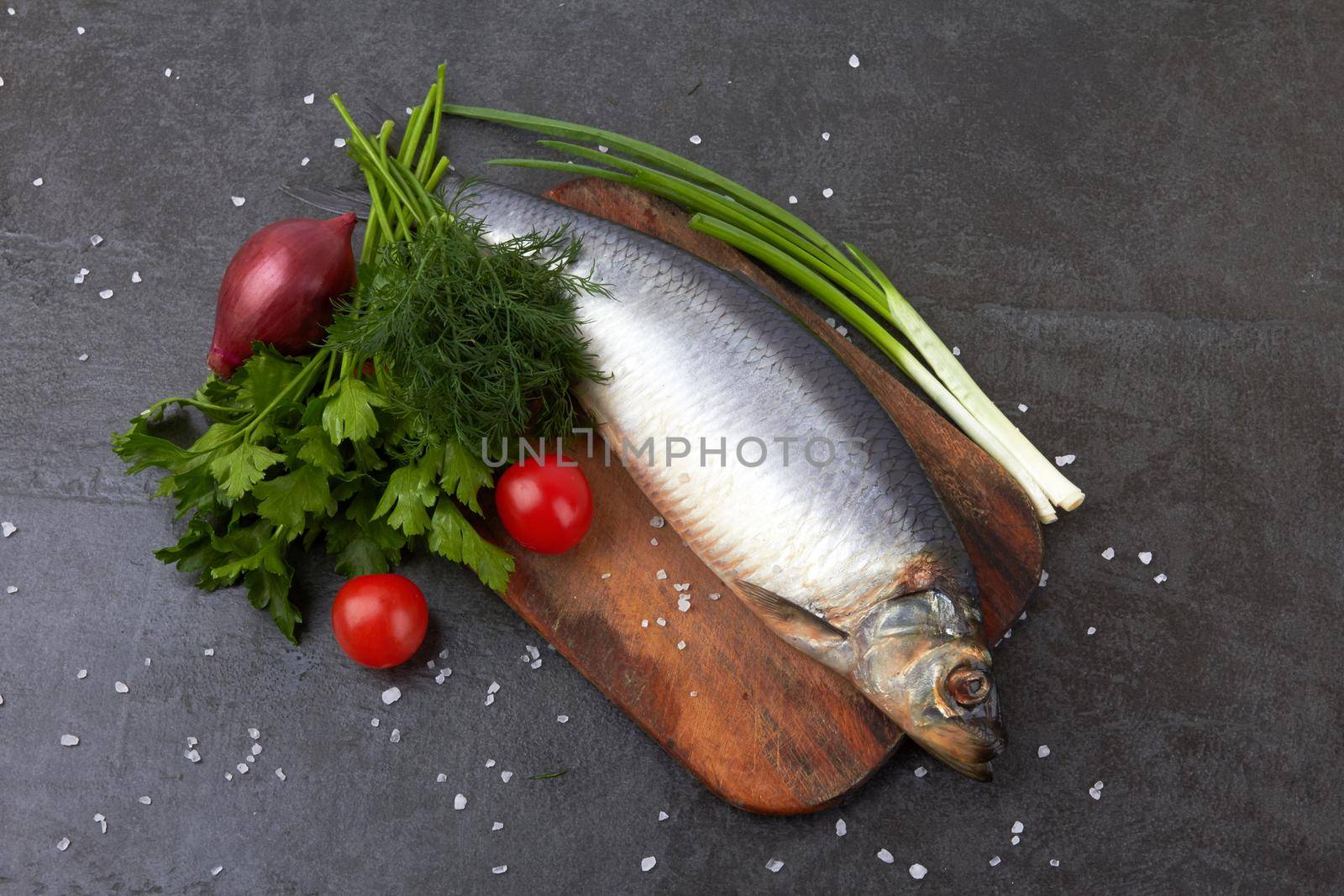Herring fish on a stone black surface