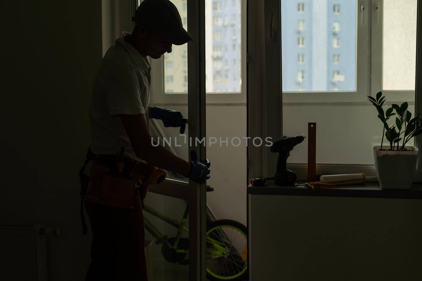 Master in gloves adjusting pvc windows with screwdriver closeup. Installation of plastic windows repair and maintenance concept