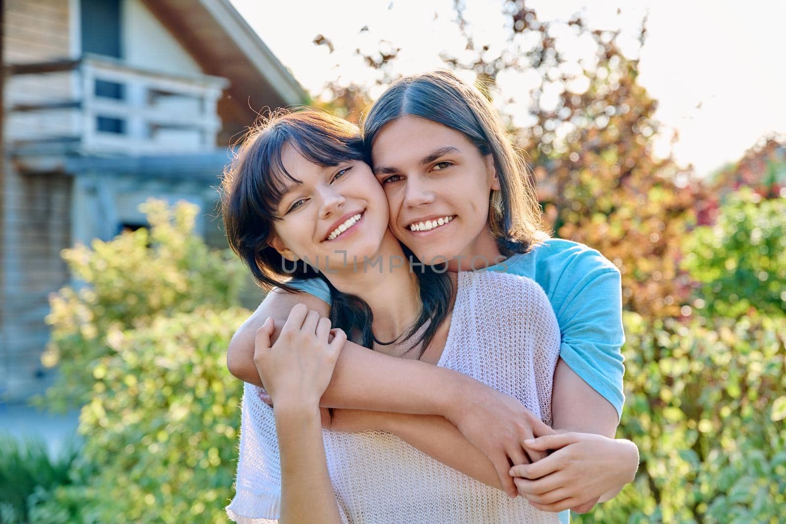 Portrait of happy couple of teenagers friends hugging together, outdoor, nature park backyard, sunny summer autumn day. Friendship, love, romantic, lifestyle, youth, young people aged 18, 19