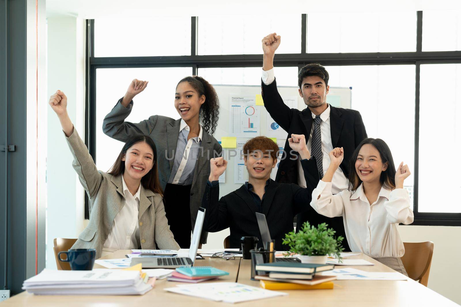 Portrait success and team work concept. Group of business partners with raised up hands in light modern workstation, celebrating the breakthrough in their company by nateemee