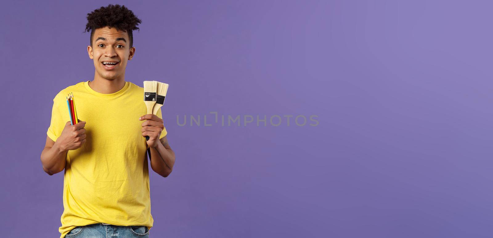 Portrait of upbeat young creative man, artist starting art courses, want to learn how to draw, holding colored pencils and brushes, standing enthusiastic over purple background by Benzoix