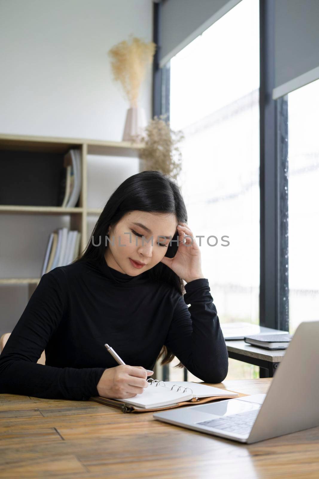 Serious young female designer working on project in office. by prathanchorruangsak