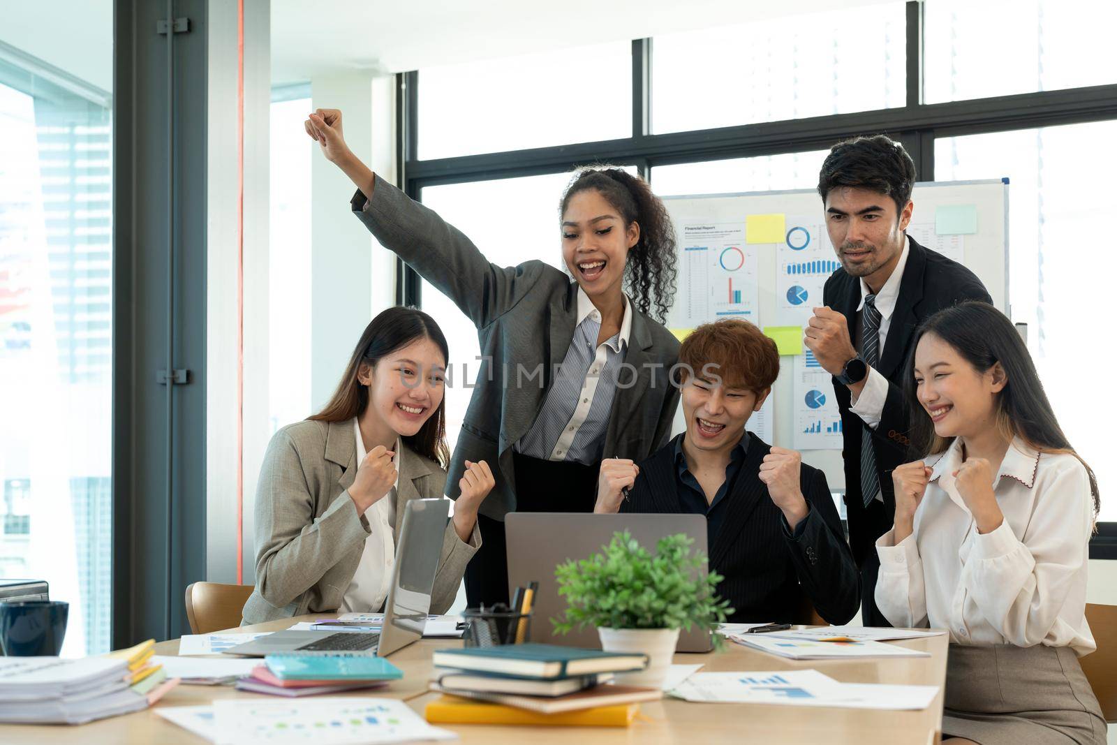 Portrait success and team work concept. Group of business partners with raised up hands in light modern workstation, celebrating the breakthrough in their company by nateemee