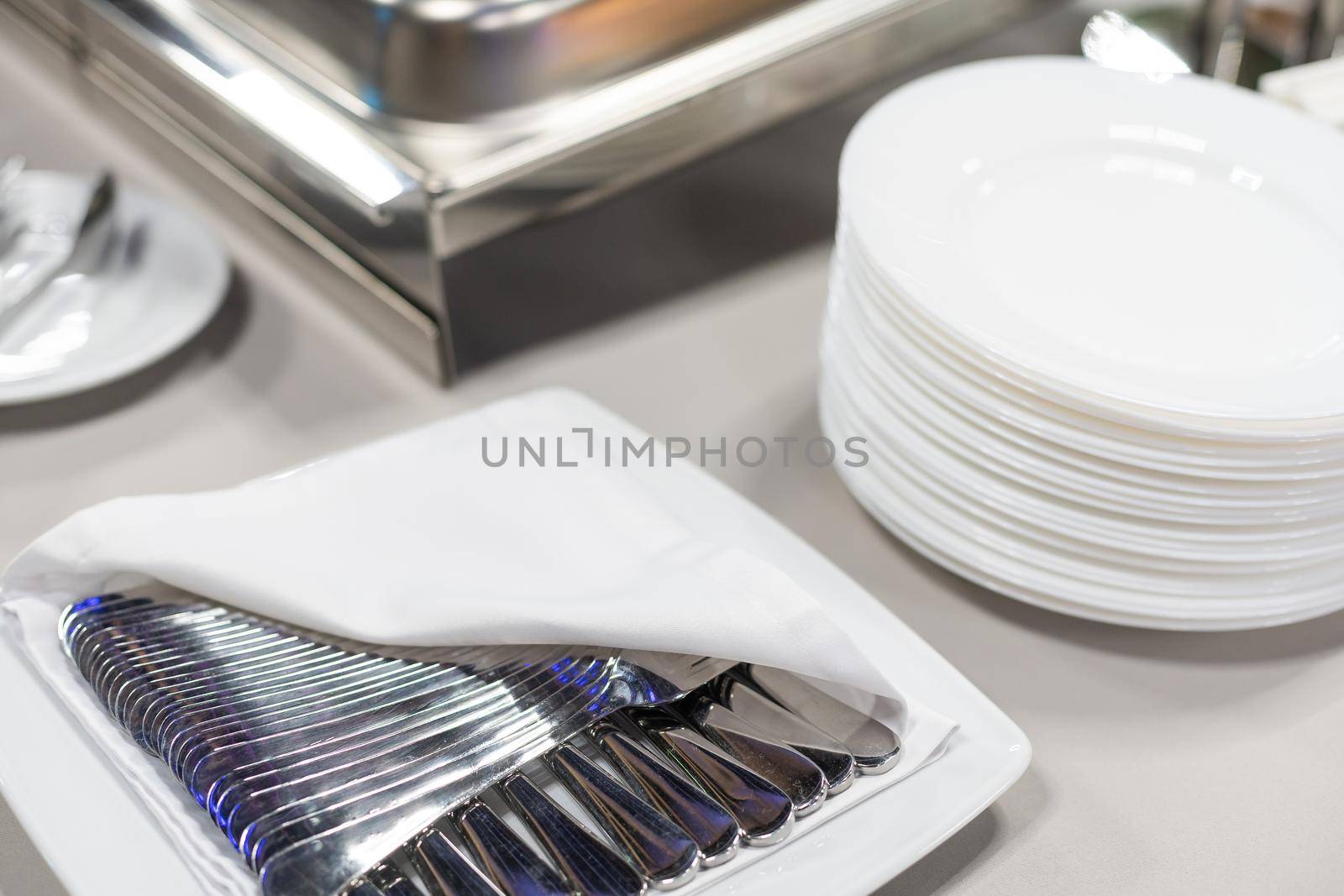Clean plates, glasses and cutlery on white table. by Andelov13
