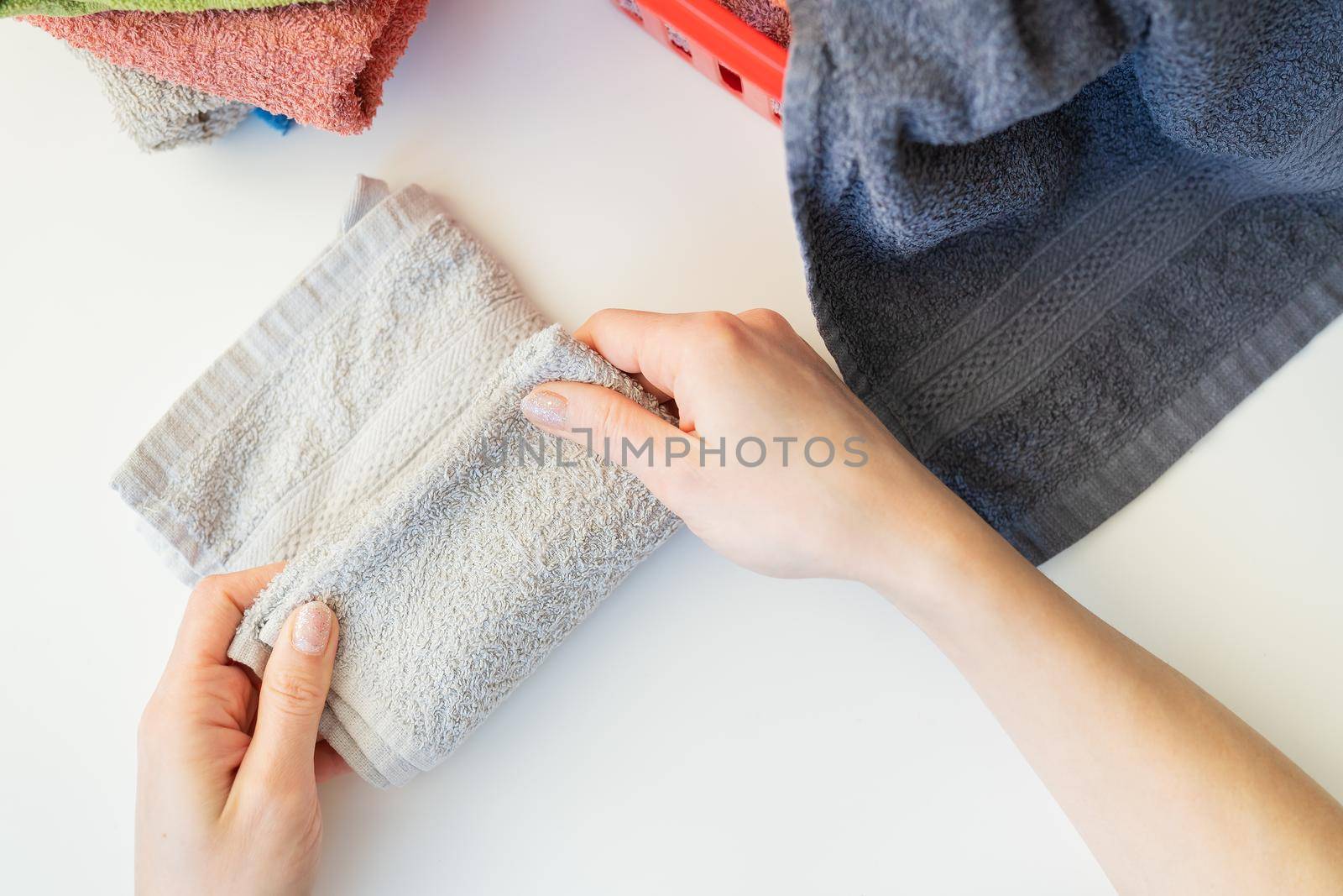 A woman's hand holds a terry towel from a clothes basket. Towel after washing. The girl folds the towel after washing, folding clothes. by sfinks