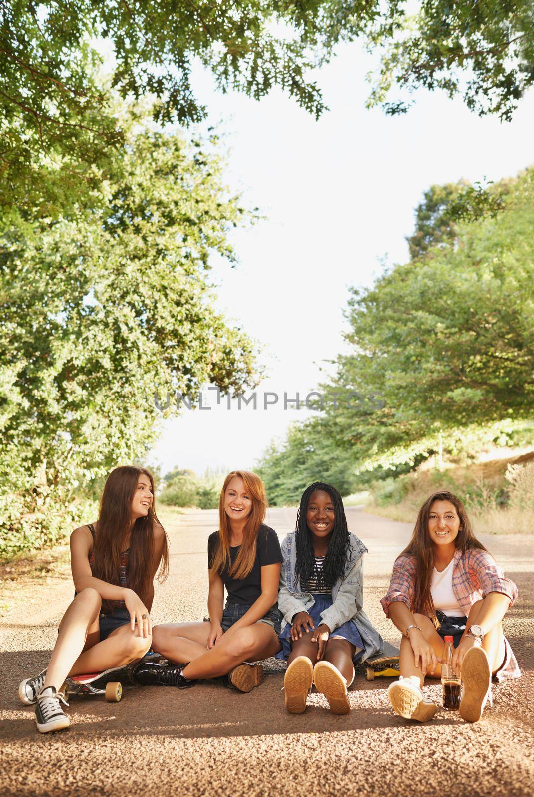 Laughter is an instant vacation. A group of multiracial teens sitting outdoors enjoying each others company. by YuriArcurs