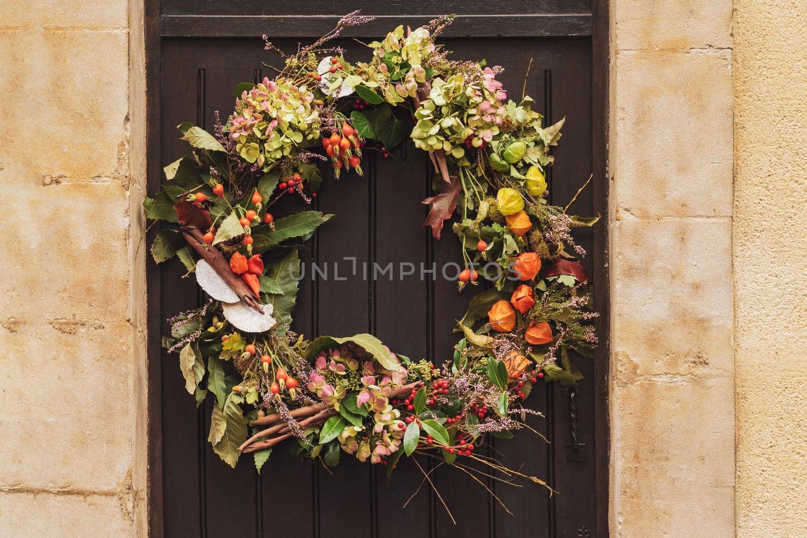 Wreath with the red berries and the dry leaves hanging on a door.
