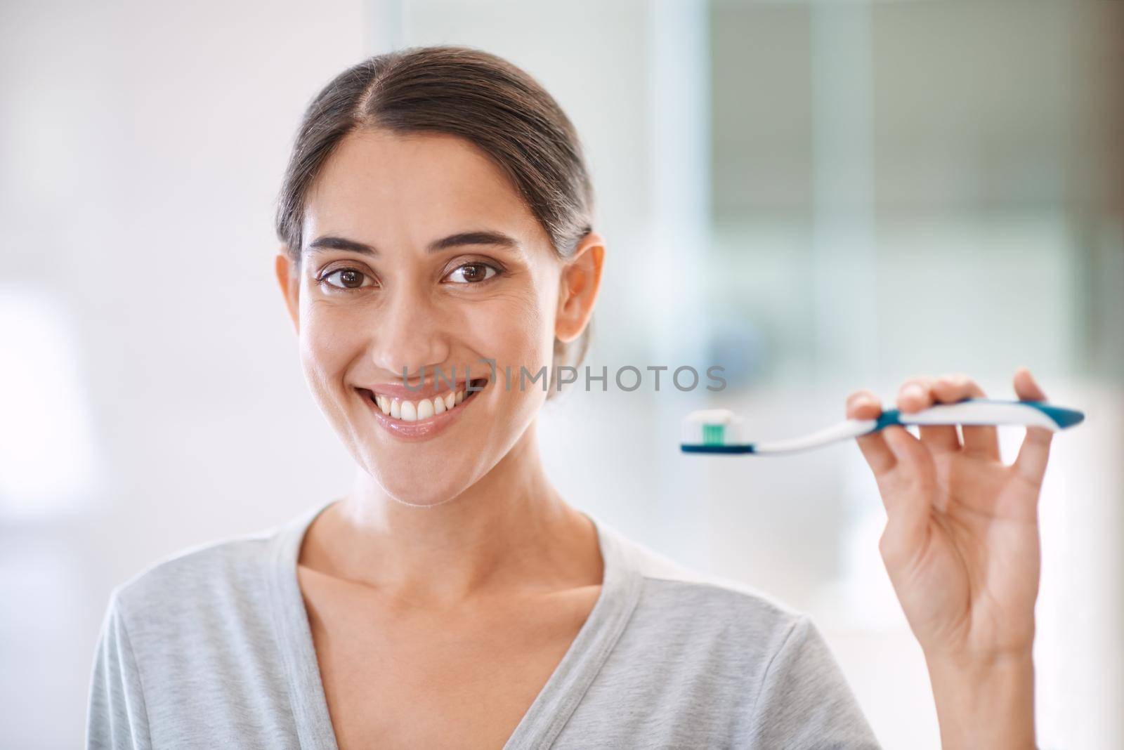 I brush three times a day. Portrait of an attractive young woman brushing her teeth