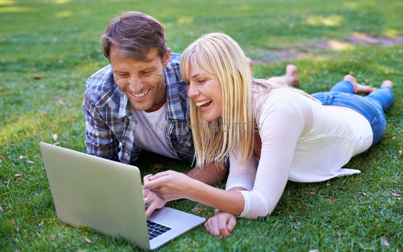 Is that your ex. an attractive couple using a laptop outdoors. by YuriArcurs