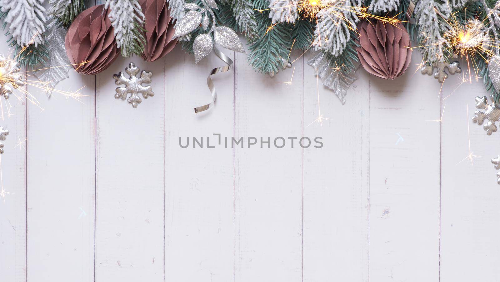 New Year Christmas flat lay with pine trees, paper Christmas toys and tinsel on wooden background with copy space.