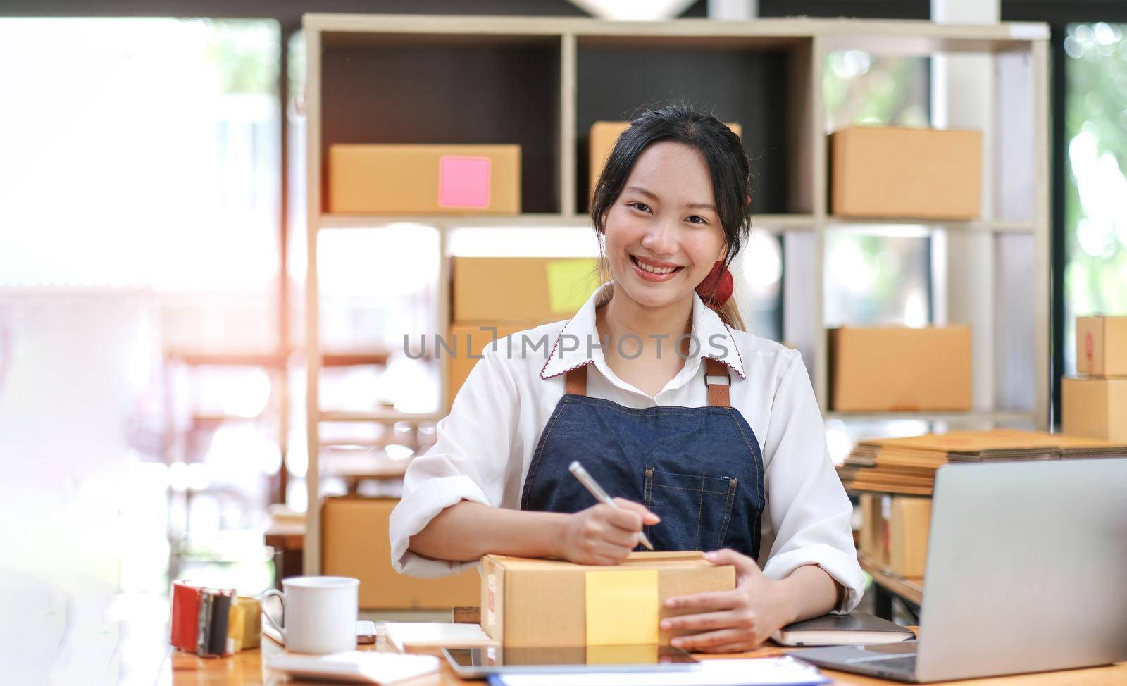 Portrait of Asian young woman SME working with a box at home the workplace.start-up small business owner, small business entrepreneur SME or freelance business online and delivery concept..