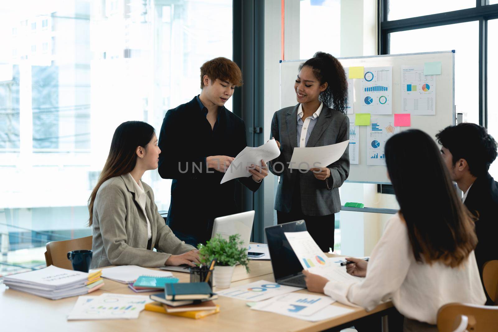 Group of diverse colleagues discussing for financial report with presentation on flipchart during a small conference in the office.