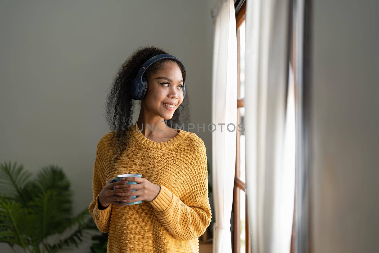 Young woman enjoying music at home. Beautiful young woman listening to the music, drinking coffee and enjoying leisure time at home by nateemee