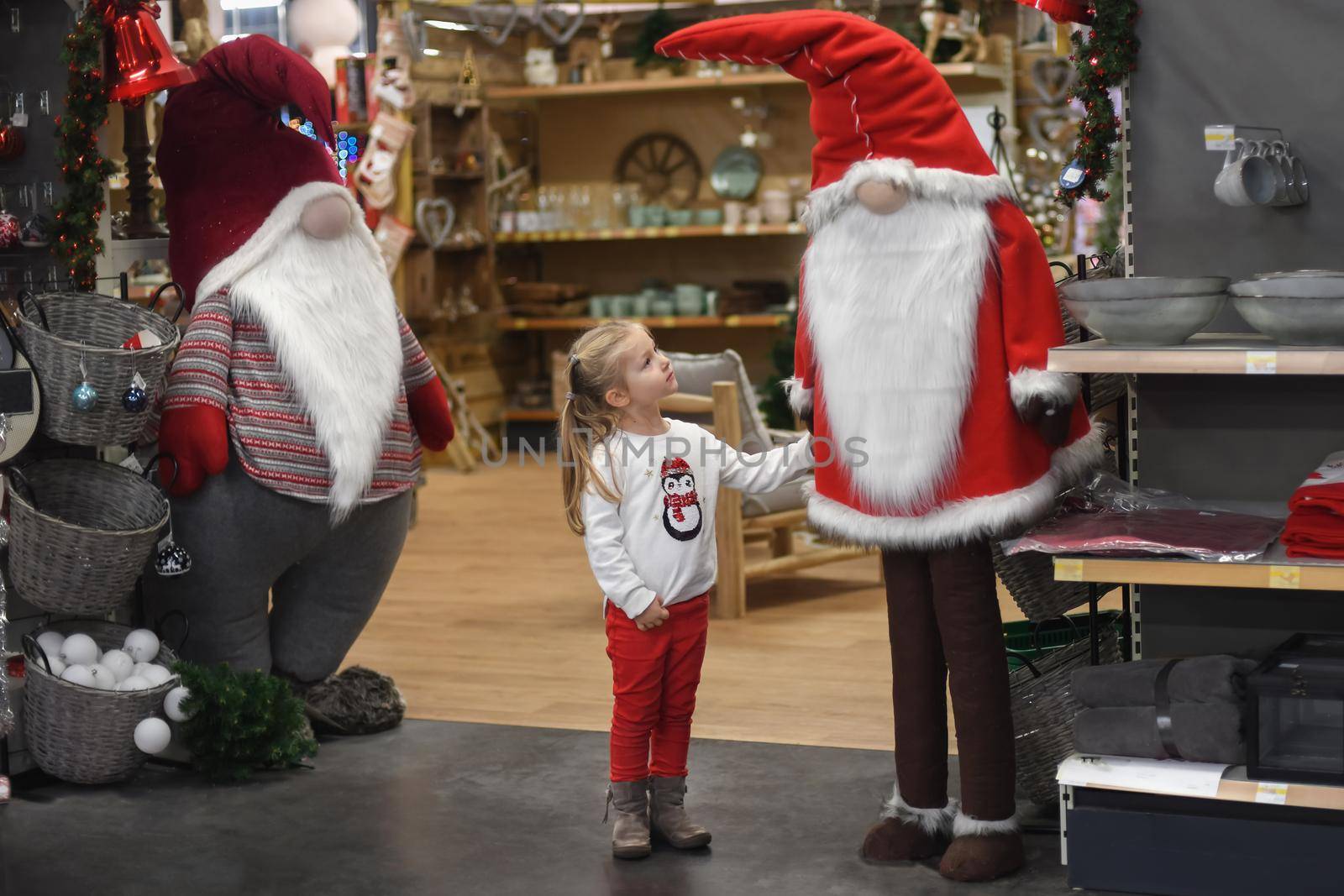 Girl looking at Santa Claus in a store with toys and decorations