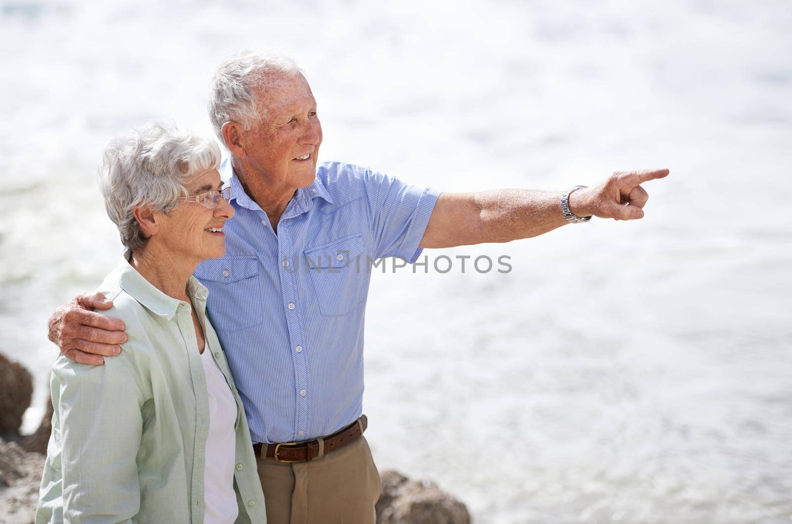 Enjoying the beauty of nature together. an elderly couple on the beach. by YuriArcurs