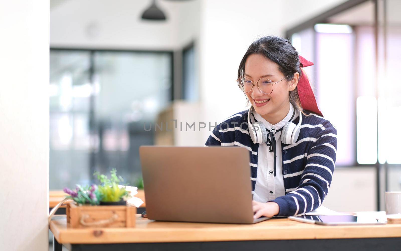 Student learning on laptop indoors- educational course or training, seminar, education online concept, Asian woman with modern laptop and headphones learning at home.