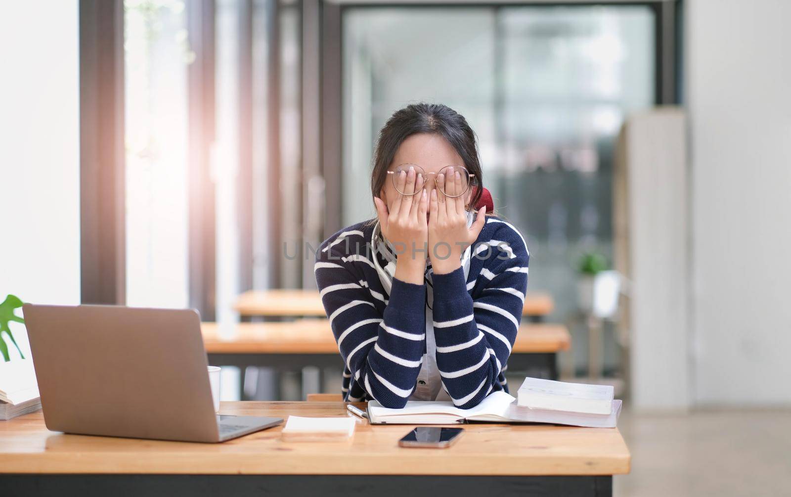 Tired young university student asian woman with stressed and headache with learn online lesson. Young female can not understand when teacher teaching on online internet by study at cafe She get bored by wichayada