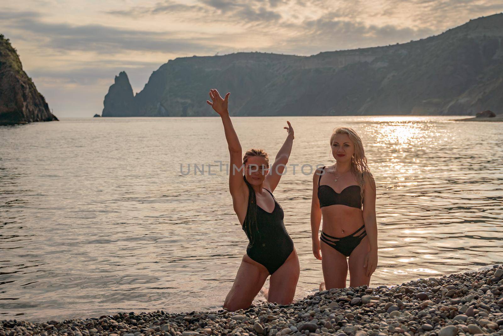 Two beautiful lgbt lesbian female friends relax and happy at the beach sitting on the sand wearing swimsuit. Travel and sea on holiday vacation. by Matiunina