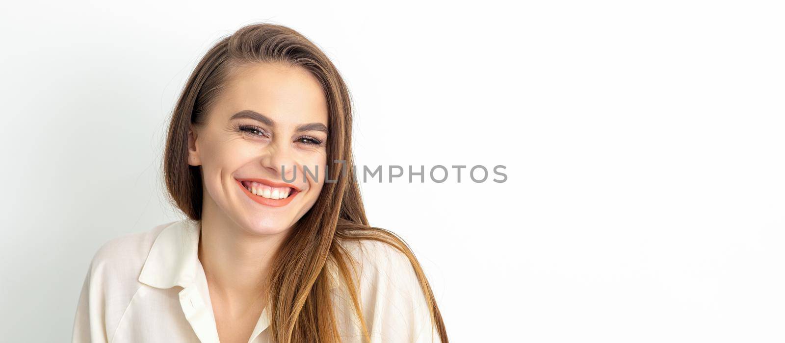 Beauty concept of woman. Portrait of a happy charming shy smiling young caucasian woman with long brown hair posing and looking at the camera over white background