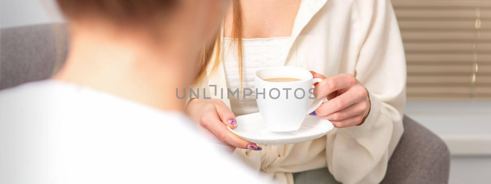 The young caucasian woman has a coffee and appointment with a female doctor in hospital office