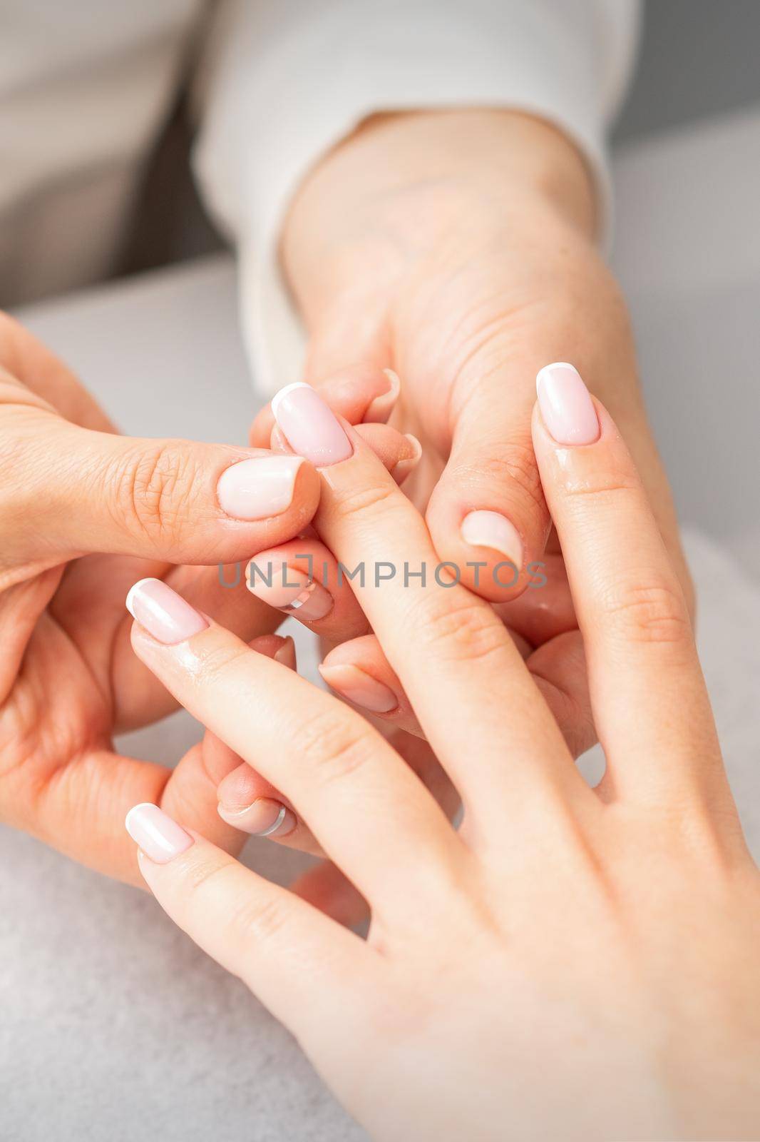 Manicure treatment at beauty spa. A hand of a woman getting a finger massage with oil in a nail salon
