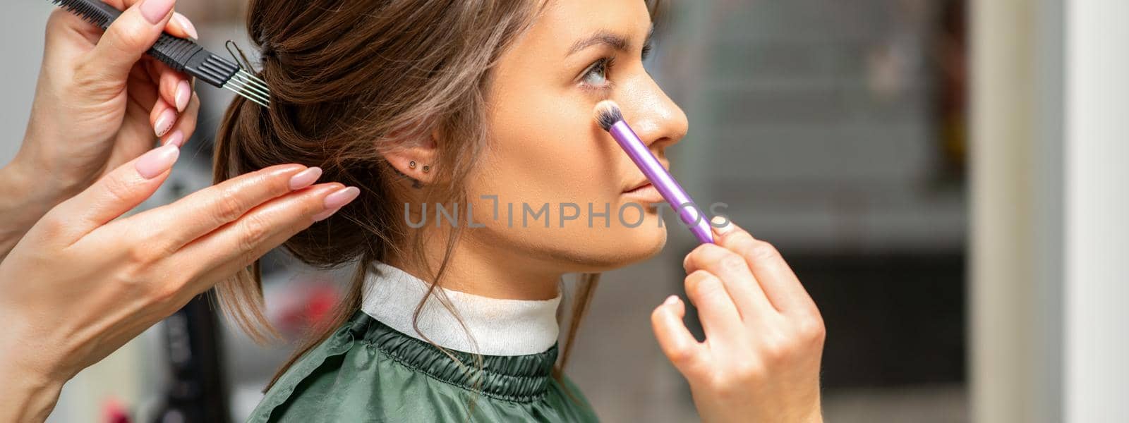 Makeup and hairstyle process. Makeup artist and hairdresser preparing young caucasian woman, working in tandem. by okskukuruza