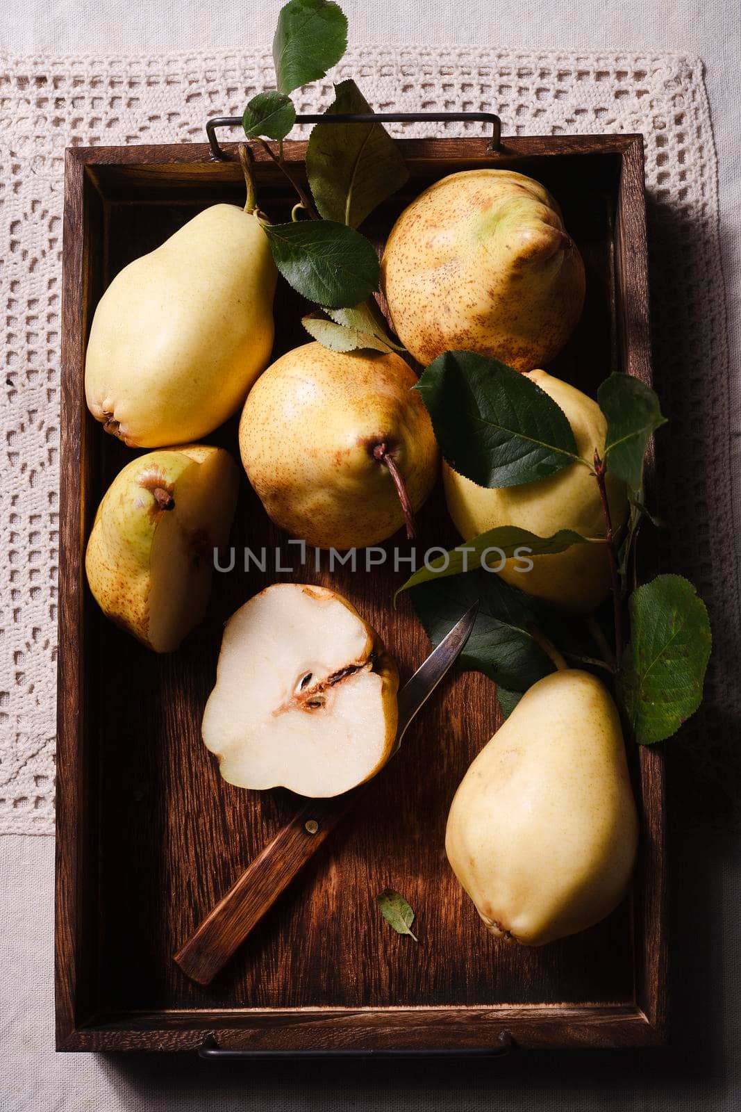 Fresh ripe yellow pears in wooden brown box in rustic kitchen, fruit harvesting concept, top view, flat lay.