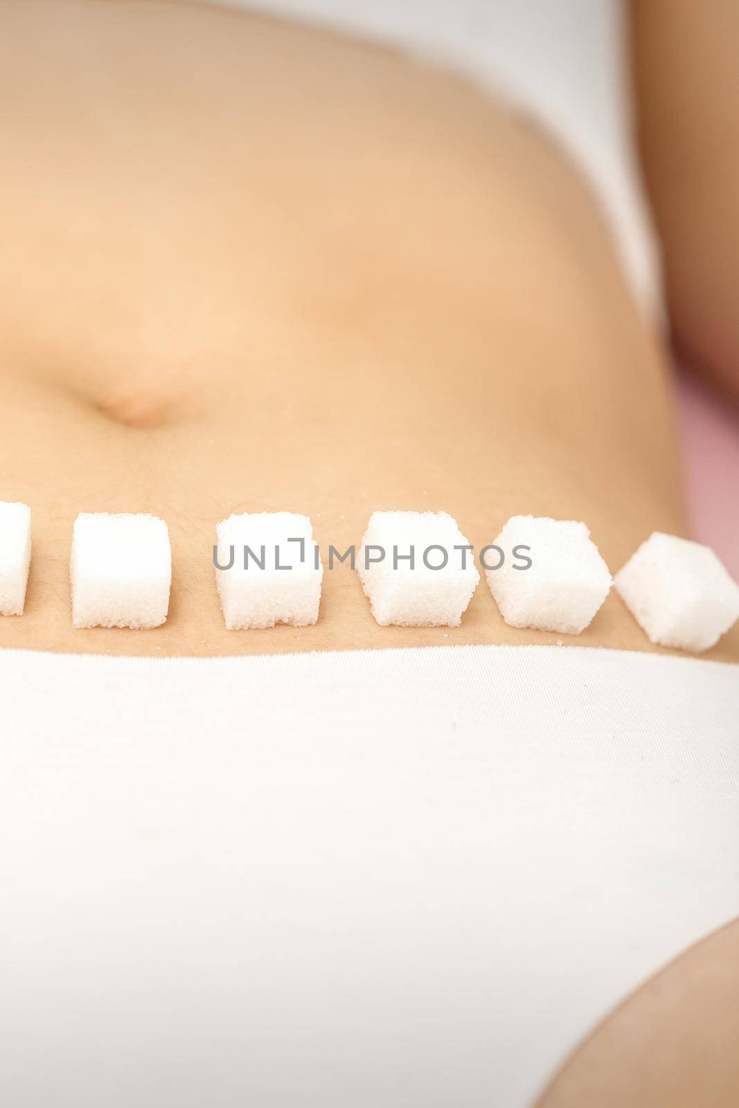 Sugar cubes lying in a row on female bikini zone, the concept of intimate depilation, problems of intimate hygiene