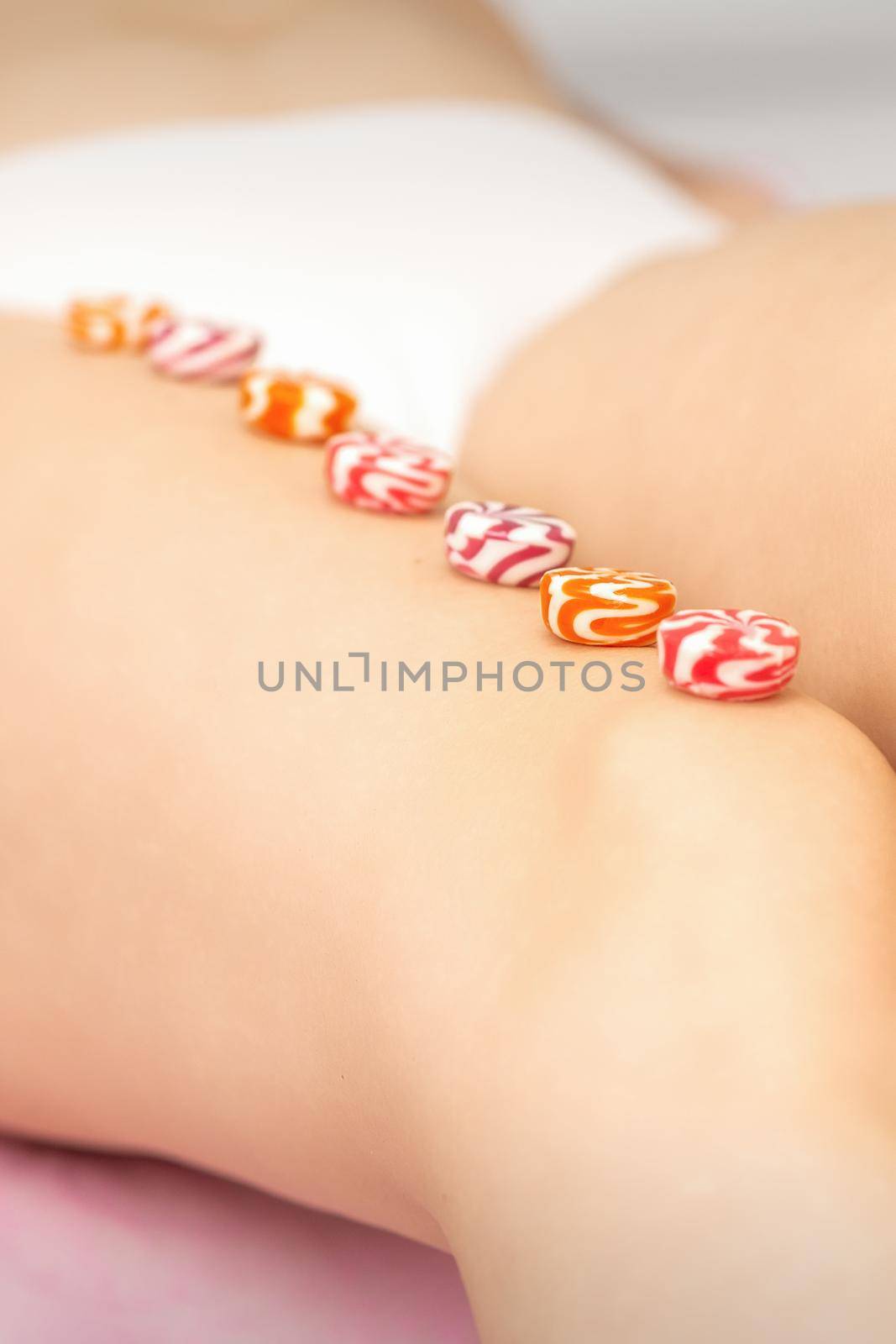 Round candies lying in a row on the female leg with copy space, depilation concept. by okskukuruza