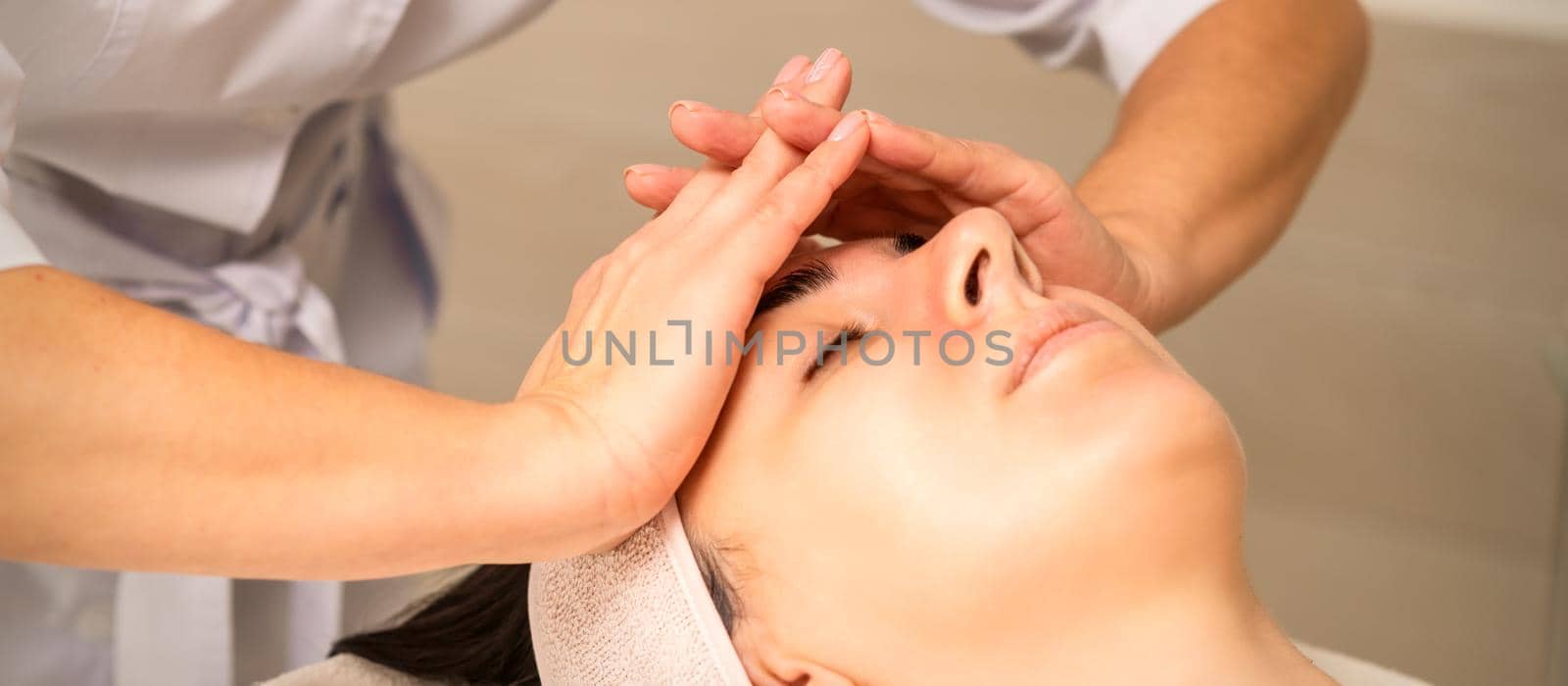 Beautiful young caucasian woman receiving a head massage in a beauty clinic, close up. by okskukuruza