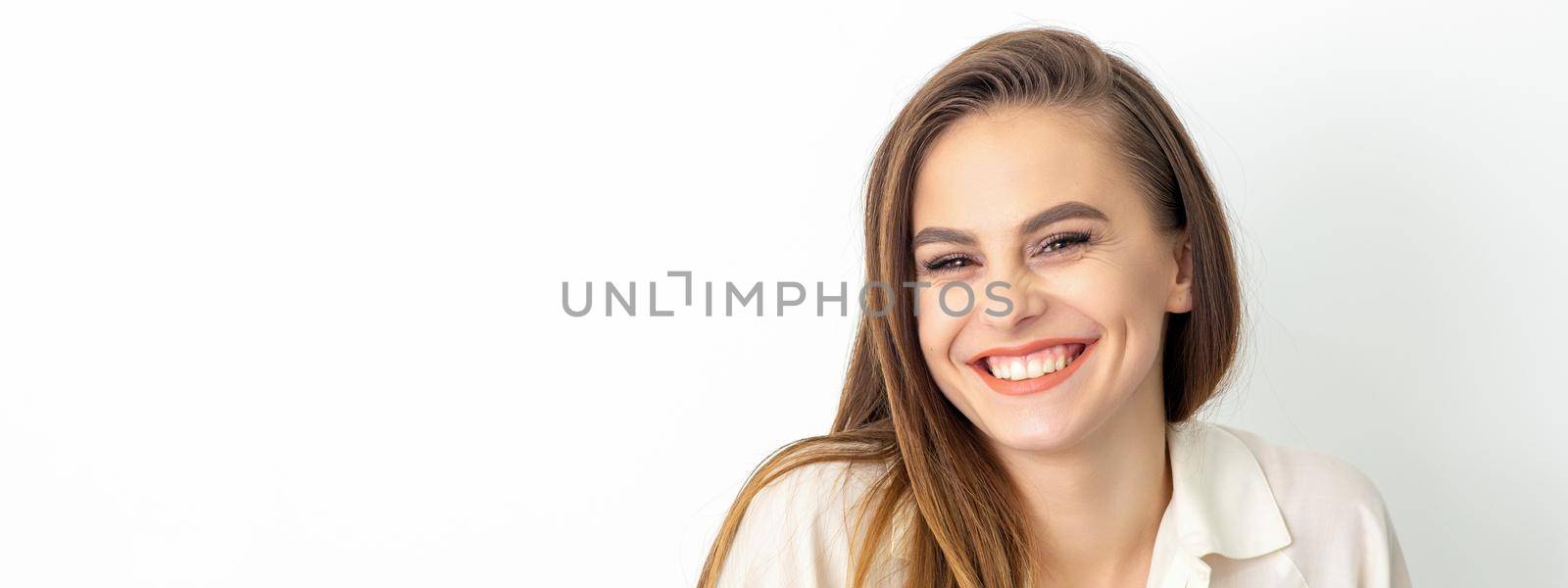 Beauty concept of woman. Portrait of a happy charming shy smiling young caucasian woman with long brown hair posing and looking at the camera over white background. by okskukuruza