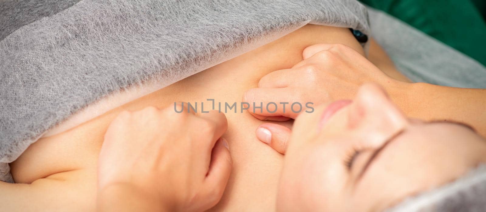 Masseuse with fists makes a chest massage of a young caucasian woman in a spa salon. by okskukuruza