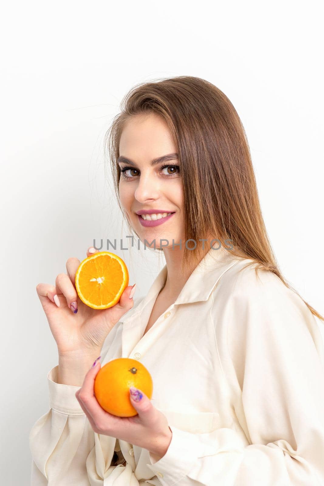 Young Caucasian smiling woman with slices orange over isolated white background. by okskukuruza