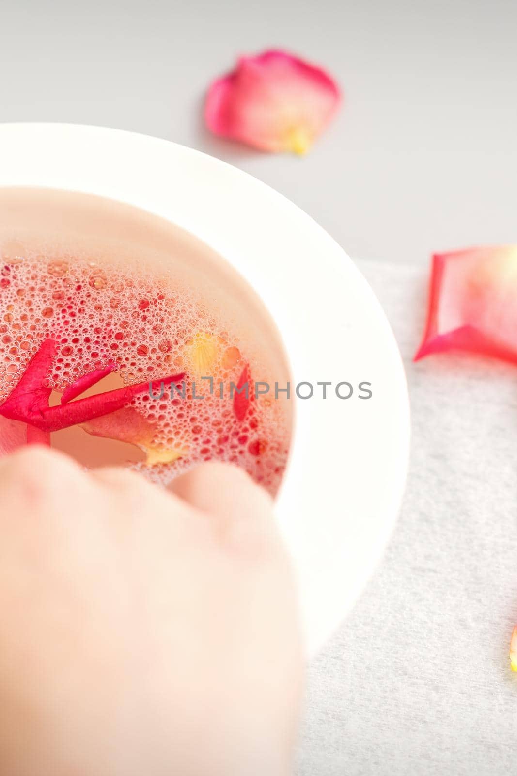 Female hands in a bowl of water with pink petals of rose flowers in spa. by okskukuruza