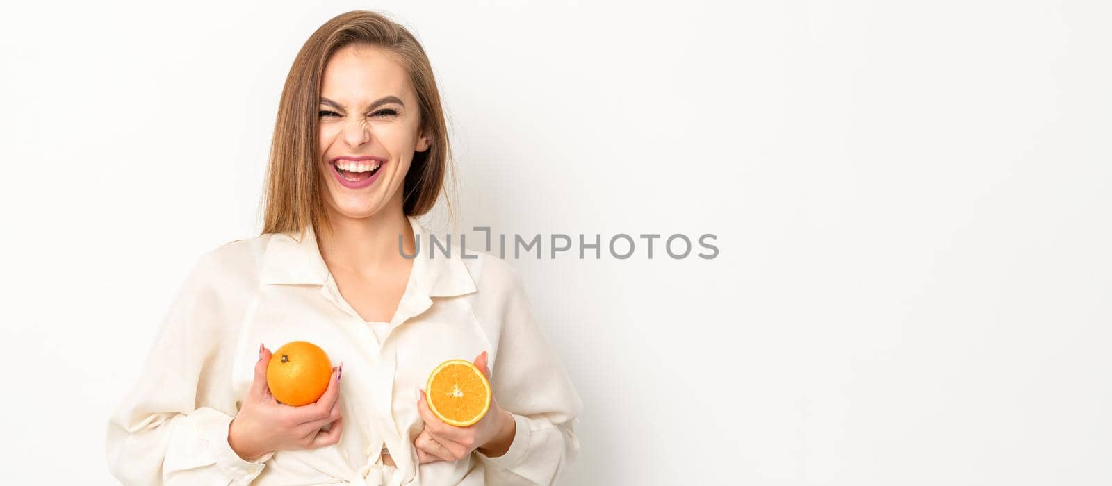 Young Caucasian smiling woman holding slices orange over isolated white background, breast health concept. by okskukuruza