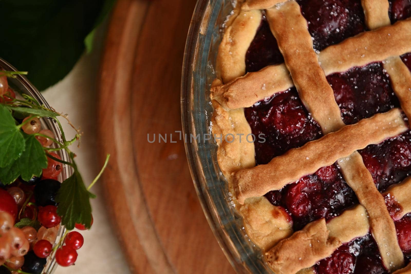 Cropped view classic American festive cherry pie with crispy sweet pastry lattice and fresh ripe organic berries in bowl by artgf