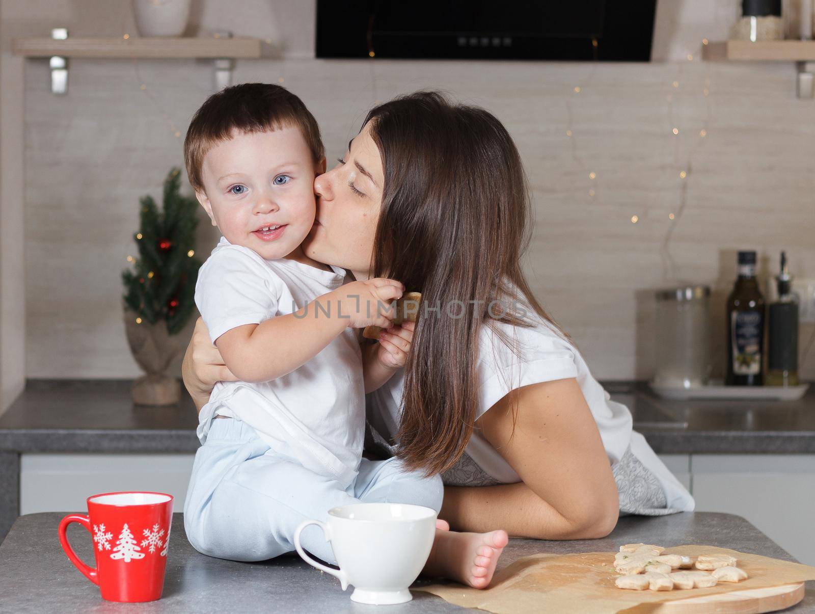 Mom kisses the child in the kitchen. A series of photos from everyday life in a real interior