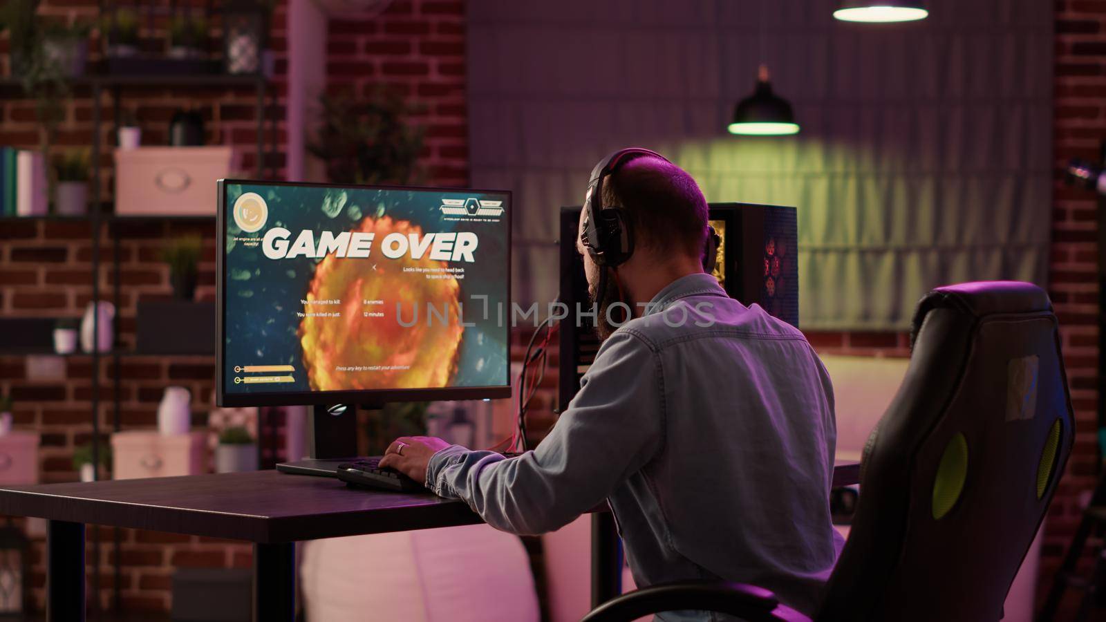 Gamer feeling disappointed after losing difficult level in online space shooter on gaming pc in home living room. Man playing internet multiplayer game sad and bored after failing tournament.