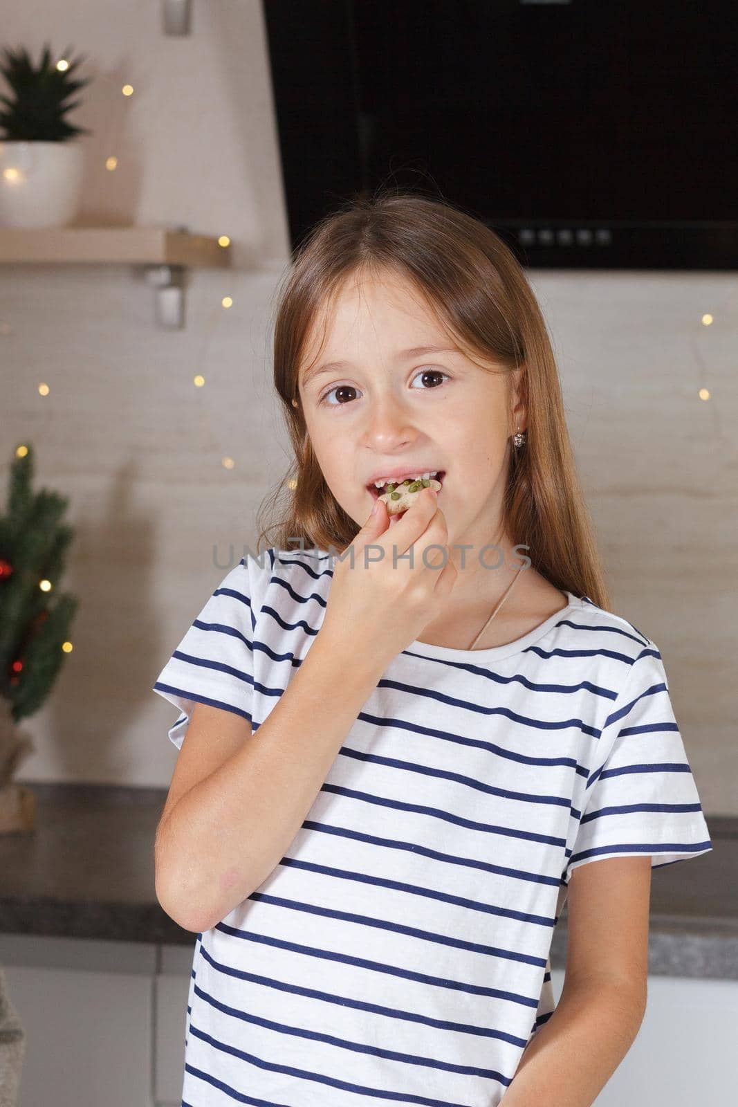 The girl eats cookies in the kitchen. Real life.