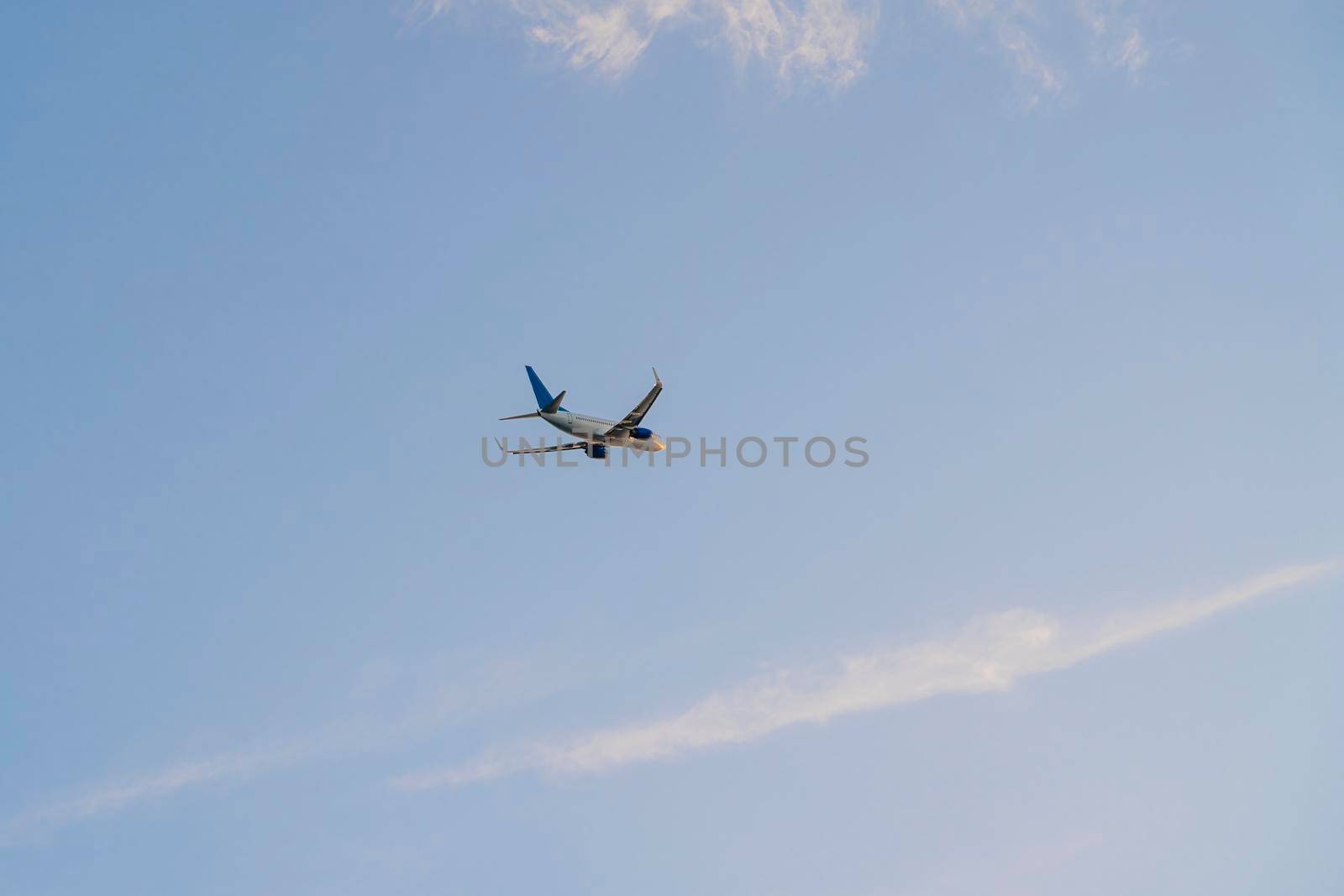 the plane is flying against the blue sky. photo