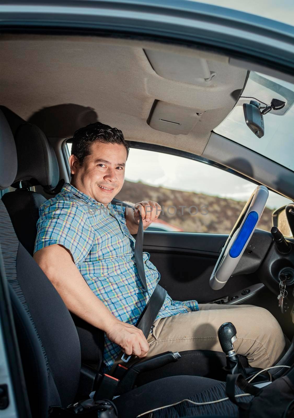 Happy driver putting on his seat belt, Smiling male driver putting on his seat belt. Concept of a driver in his car putting on his seat belt. Smiling person putting on seat belt
