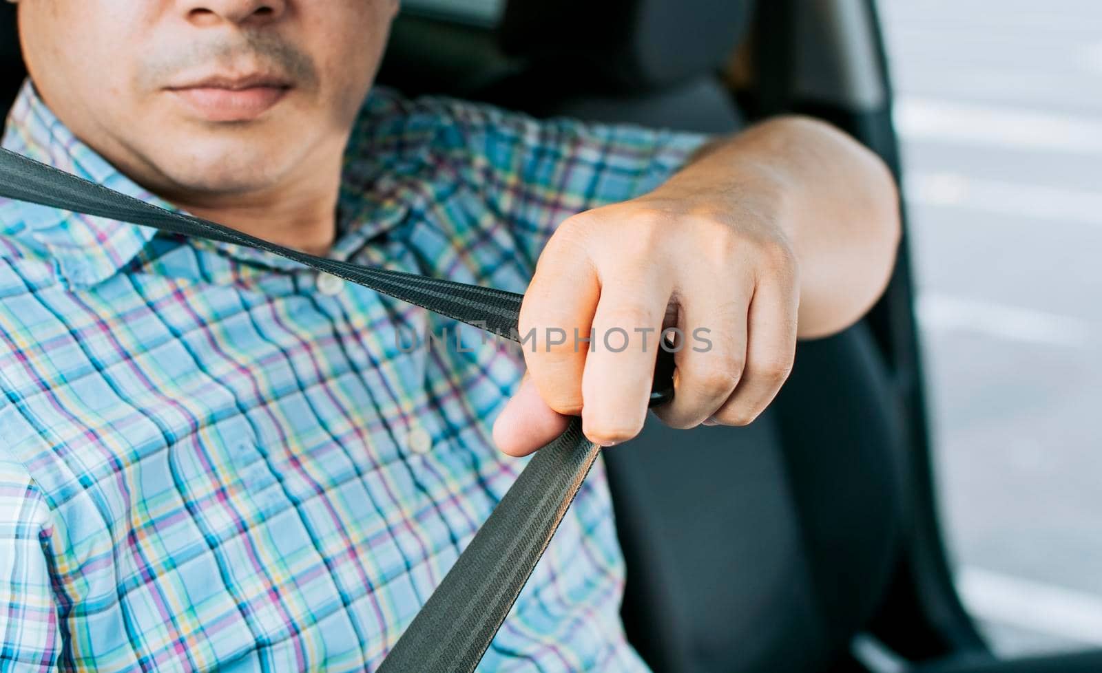 Safety belt for accident prevention. Driver hands fastening the seat belt, Close up of person hands putting on the seat belt. Driver's hands putting on the seat belt