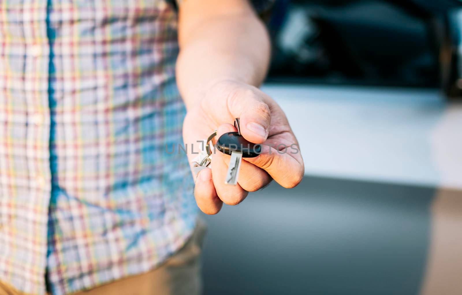 Driver's hands showing the car keys, Close-up of male driver hands showing the keys, Vehicle rental concept. Close-up of people holding car keys by isaiphoto