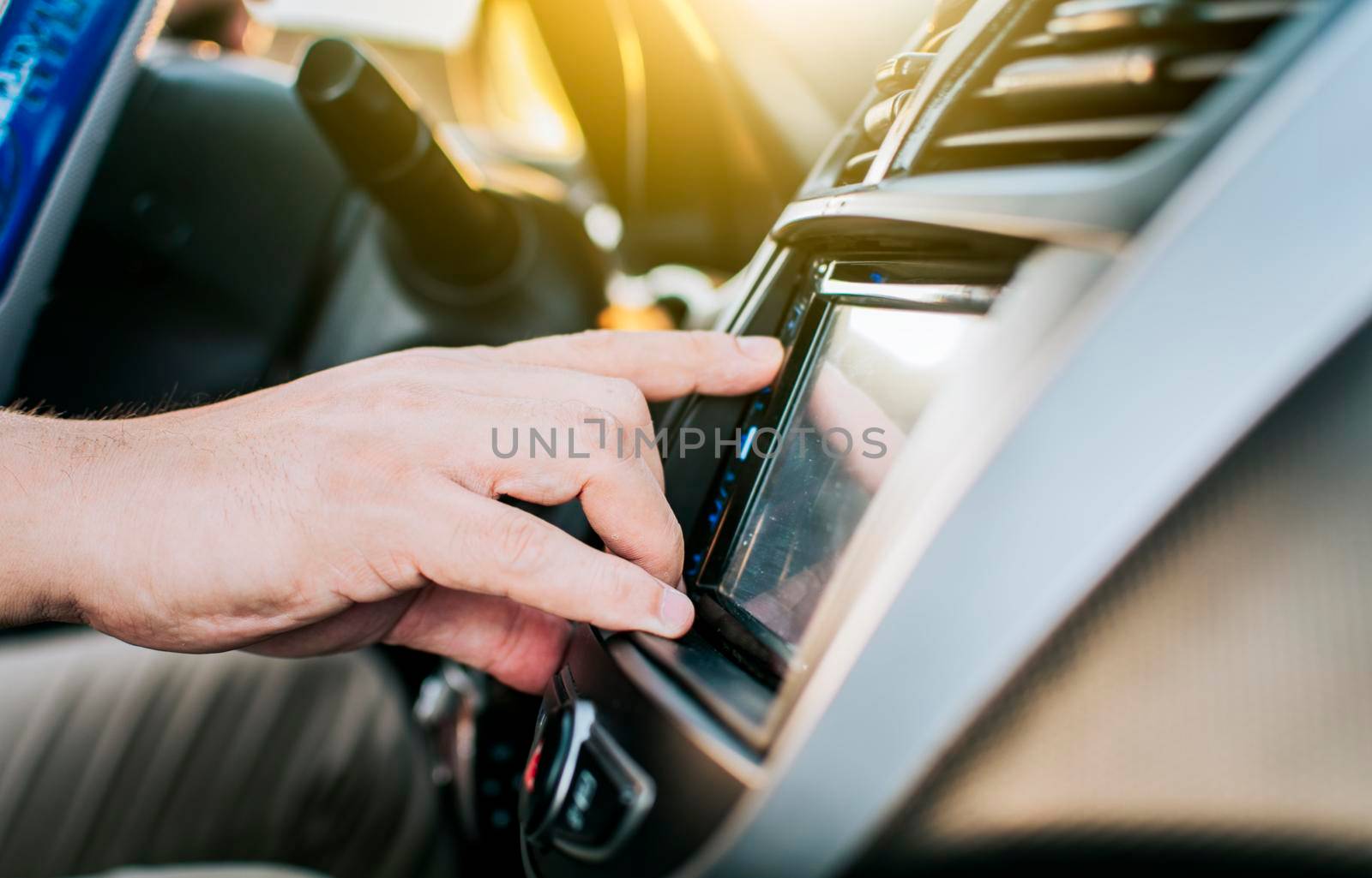 Close up of hands changing the car radio station. Concept of driver tuning the radio. Driver man changing radio station, Driver hands changing the radio station by isaiphoto