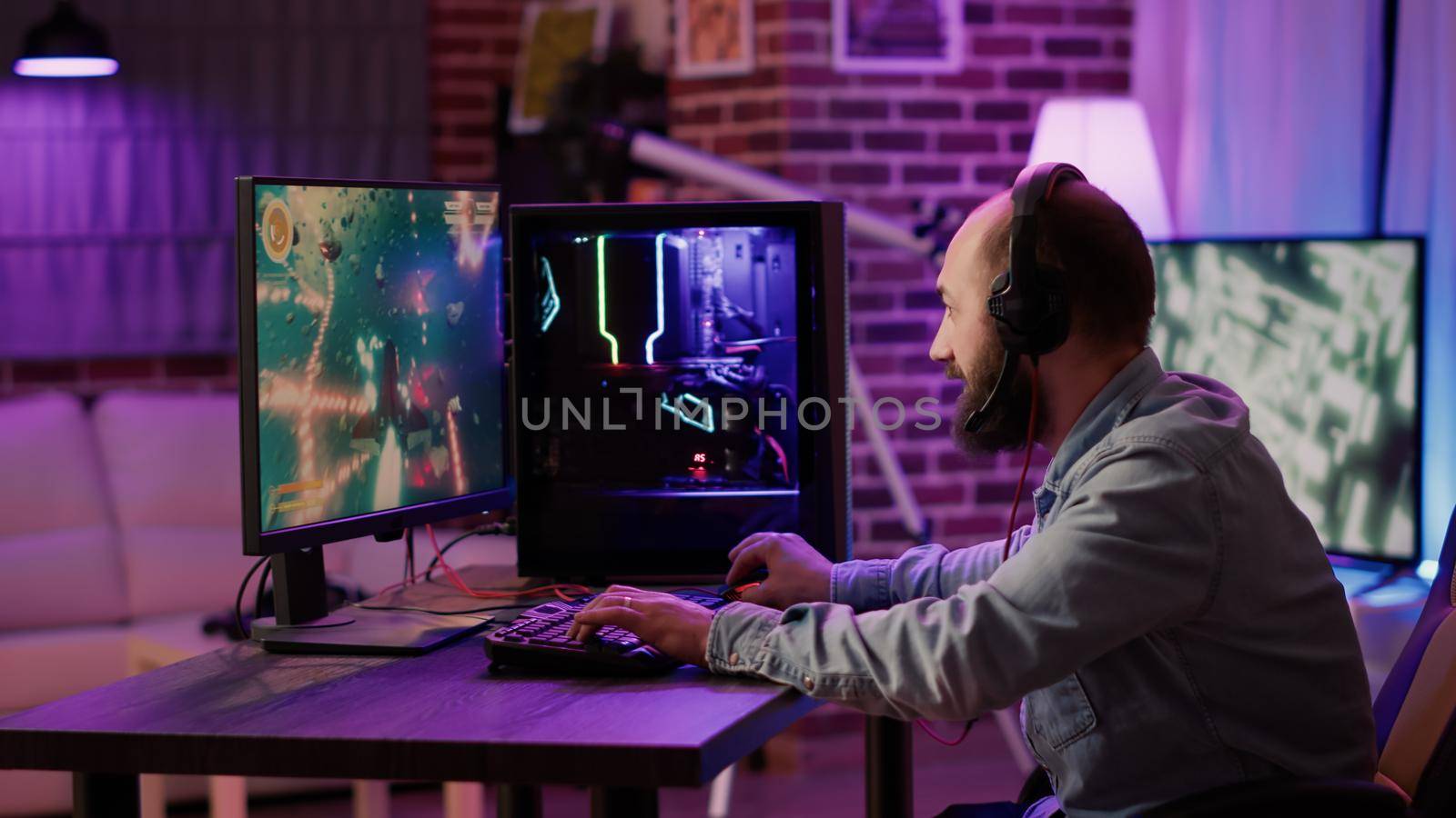 Handheld shot of gamer streaming fast paced space shooter on gaming pc setup while explaining gameplay to subscribers. Caucasian man playing multiplayer online action game talking to team on headset.