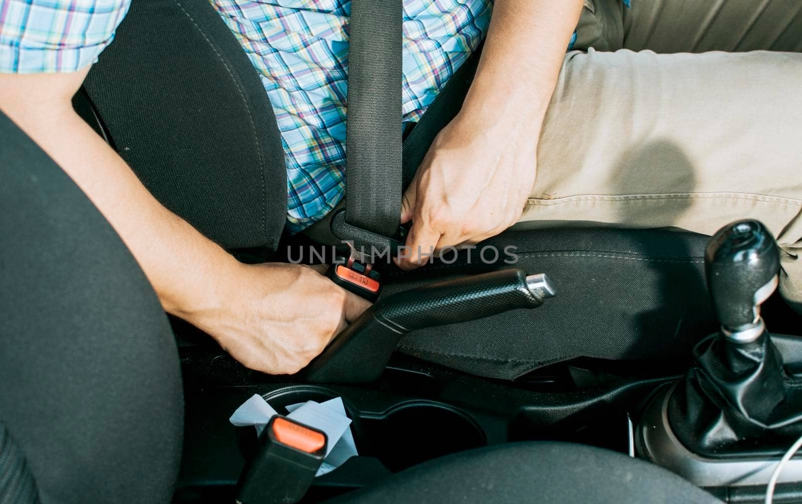 Close up of driver hands fastening the seat belt, Driver's hands putting on the seat belt. Safety belt for accident prevention. Close up of person's hands putting on the seat belt