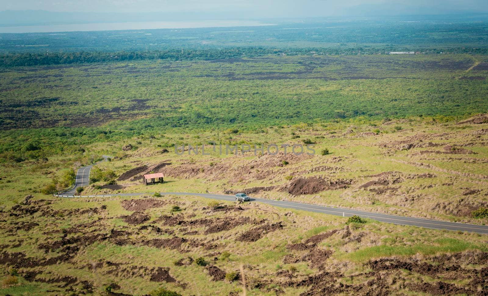 A car traveling on a paved road in the countryside. Aerial view of a car traveling on a country road in the countryside. Landscape of a car traveling on an asphalt road in the beautiful countryside